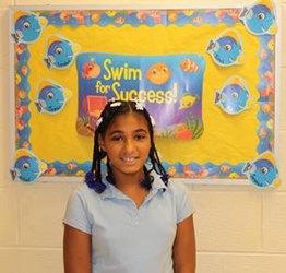 Girl Standing in front of a sign that says Swimming for Success